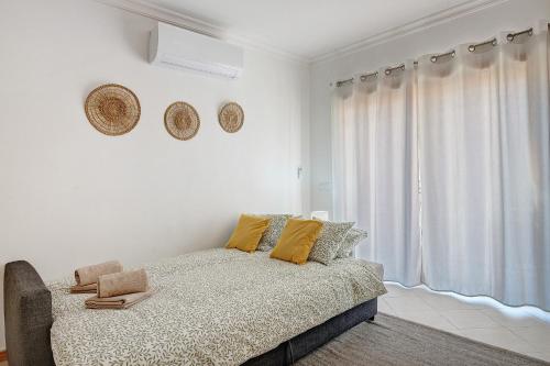 a white bedroom with a bed and a window at Casa Essência in Armação de Pêra