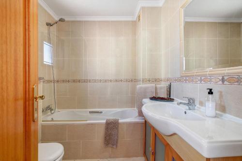 a bathroom with a sink and a tub and a toilet at Casa Essência in Armação de Pêra