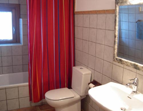 a bathroom with a toilet and a red shower curtain at Bordaberri in Ciáurriz