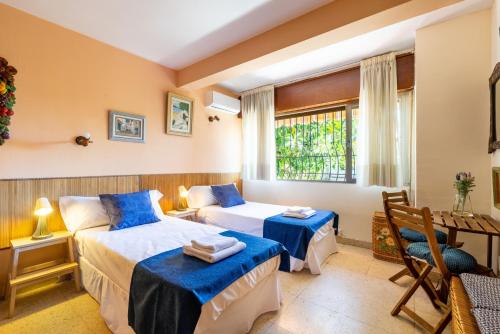 a bedroom with two beds and a table and a window at Villa La bicicleta azul in Málaga