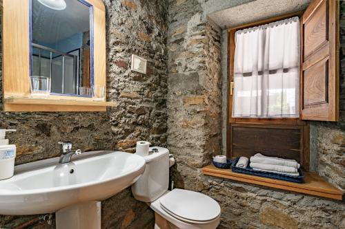 a bathroom with a sink and a toilet and a mirror at Casa Rural Casa Mario in Cangas del Narcea