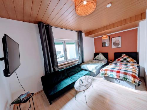 a room with a bed and a couch and a tv at Wat Bickenbach in Bickenbach