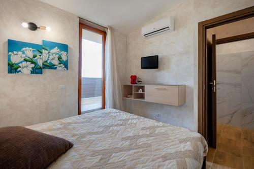 a bedroom with a bed and a window and a television at Villa Marzla in Cassano delle Murge