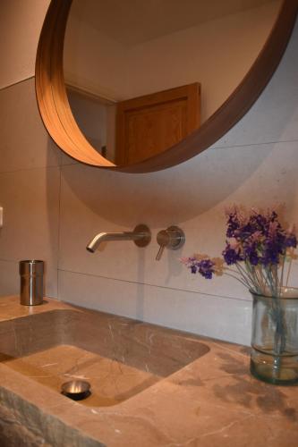 a bathroom sink with a mirror and a vase of flowers at Finca Can Nou in Sóller