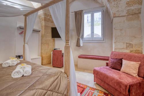 ein Schlafzimmer mit Himmelbett und rotem Stuhl in der Unterkunft Antony Suite Strada in Lecce