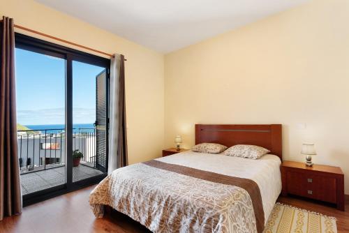 a bedroom with a bed and a large window at Casa da Pontinha in Machico