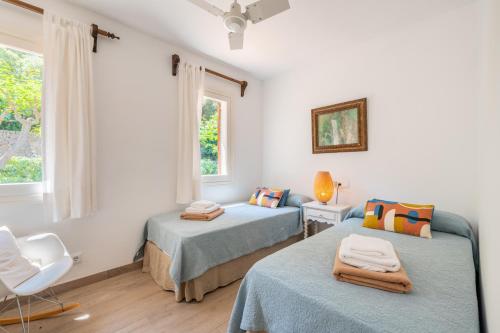 a bedroom with two beds and a chair and a window at Can Botana 12 in Cala de Sant Vicenc