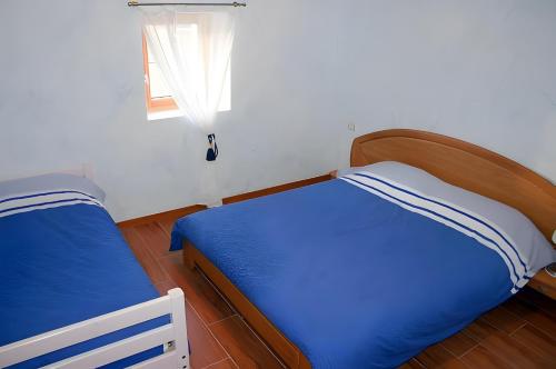 a bedroom with a blue bed and a window at Le Genévrier - Gites Rocheflamme in La Malène