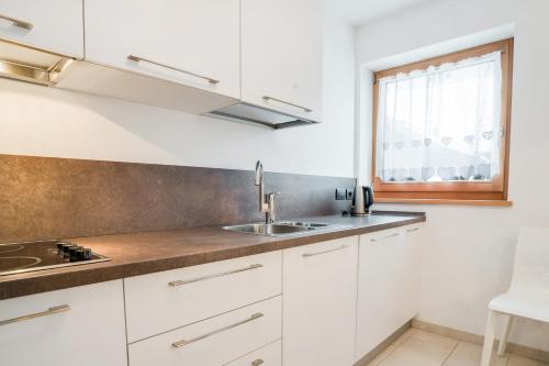 a kitchen with white cabinets and a sink and a window at Il Mondo di Patty 3 in Pera