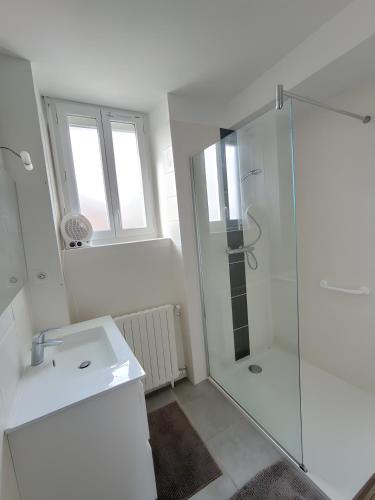 a white bathroom with a shower and a sink at Gîte des Bruyeres in Beynat