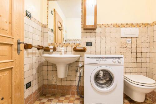 a bathroom with a toilet sink and a washing machine at Maso Noce Ovest in Mezzana