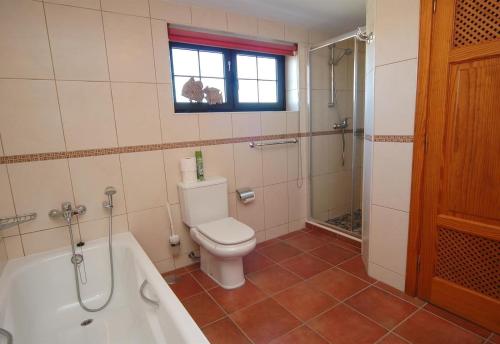 a bathroom with a toilet and a tub and a window at Finca el Volcan in Mácher