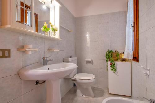 a white bathroom with a sink and a toilet at Casetta paradiso in Costa Paradiso