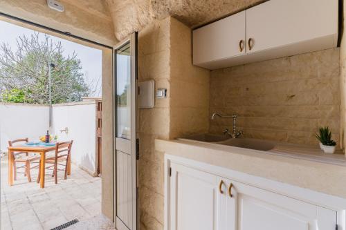 a kitchen with a sink and a sliding glass door at Corte Cochlea Lu Sciardinu Suite in Cannole