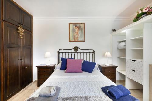 a bedroom with a bed with blue and purple pillows at El Almendro in Puntagorda