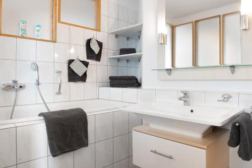 a white bathroom with a sink and a bath tub at Zeughaus Ferienwohnung in Überlingen
