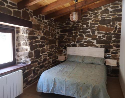 a bedroom with a bed in a stone wall at Casa Rural El Picón in Entrambasaguas