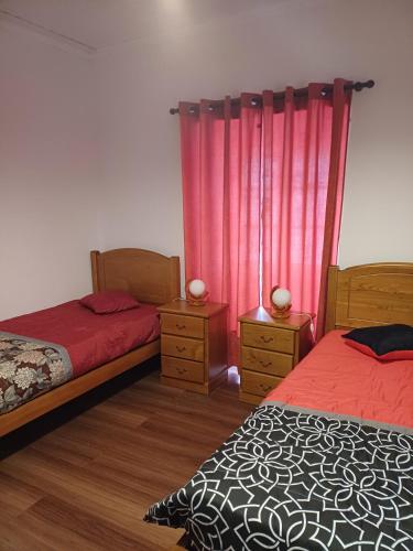a bedroom with two beds and pink curtains at Casa do Rossio in Fajazinha