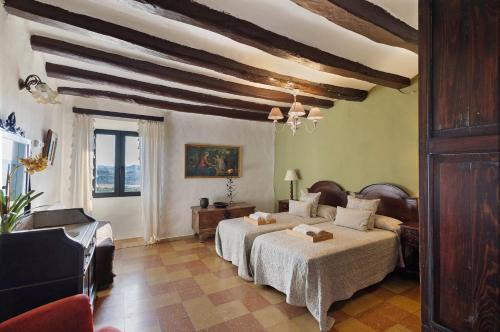 a bedroom with two beds and a ceiling with beams at Casa Espigol in El Bruc