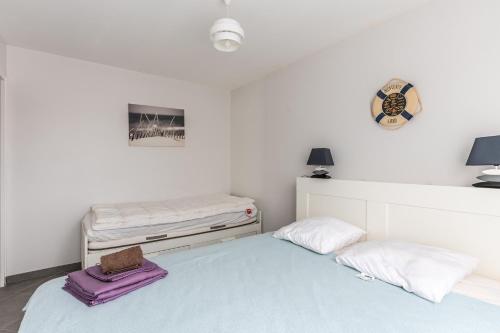 a white bedroom with a bed and two pillows at Entre plage, forêt et villages in Mimizan