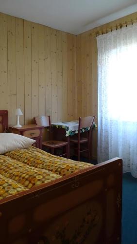 a bedroom with a bed and a table and a window at La Capinera Canazei Apartments in Canazei