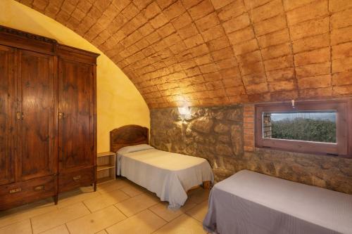 a bedroom with two beds and a stone wall at Volta De Ferreres in Olvan