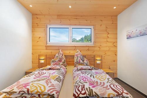 zwei Betten in einem kleinen Zimmer mit Fenster in der Unterkunft Mettmapark - 2 Chalets in Grafenhausen