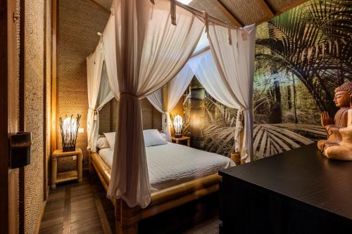 a bedroom with a canopy bed with curtains at Chalet Bangli in Lacanau