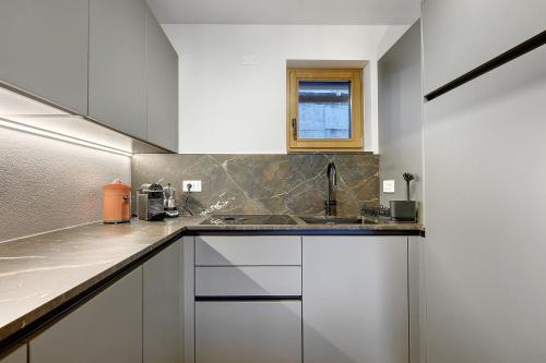 a kitchen with white cabinets and a sink at Rostrini Family Home Retreat in Cavalese