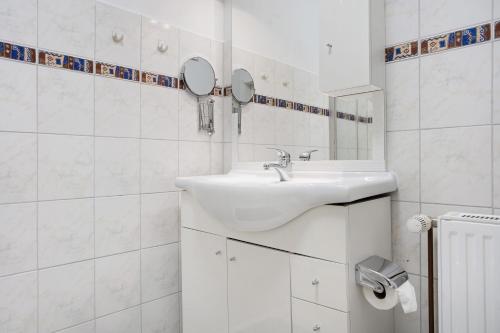 a white bathroom with a sink and two mirrors at Ferienwohnung oberhalb vom Hafen 1 in Sassnitz