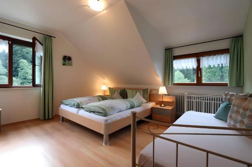 a bedroom with a bed and two windows at Gasthaus Zur Linde Ferienwohnungen in Oberharmersbach