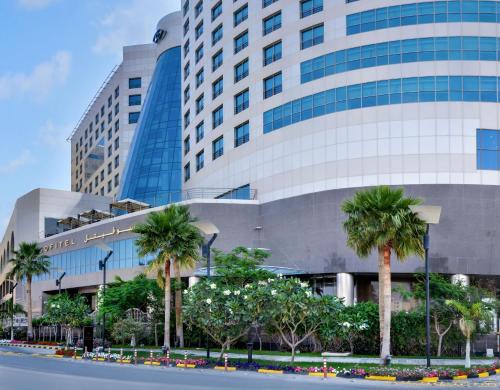 a large building with palm trees in front of it at Sofitel Al Khobar The Corniche in Al Khobar