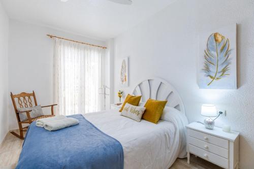 a white bedroom with a bed and a chair at Fidalsa Bay View Romance in Guardamar del Segura