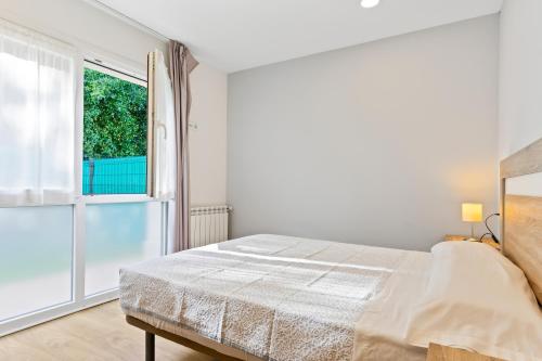 a white bedroom with a bed and a window at 2 Jardin 1 - Toró in Llanes