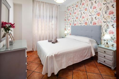 a bedroom with a white bed with a blue headboard at Torre Playa in Torre del Mar