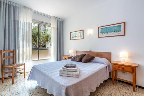 a bedroom with a bed and a chair and a window at Omega 7 in L'Estartit