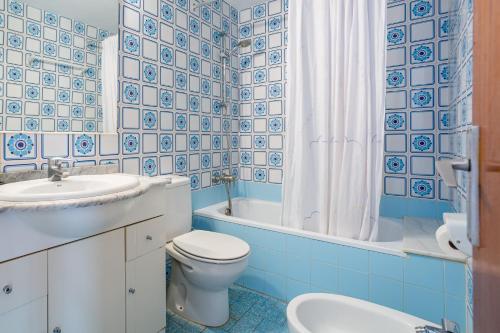 a blue and white bathroom with a toilet and a sink at Omega 7 in L'Estartit
