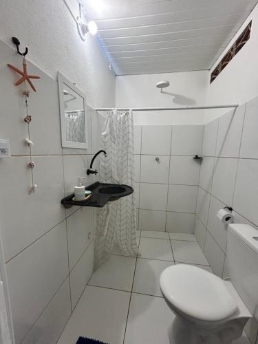 a white bathroom with a toilet and a sink at Suite Canoa azul 1 in Aracati