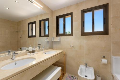 a bathroom with two sinks and a toilet and windows at Casares Beach luxe penthouse in Casares
