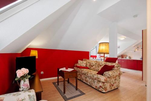 a living room with a couch and a red wall at Fewo Birkenallee - Rose in Deinste