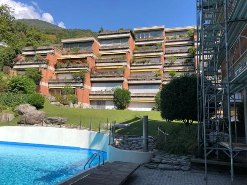 a building with a swimming pool in front of a building at Appartement im Park in Minusio