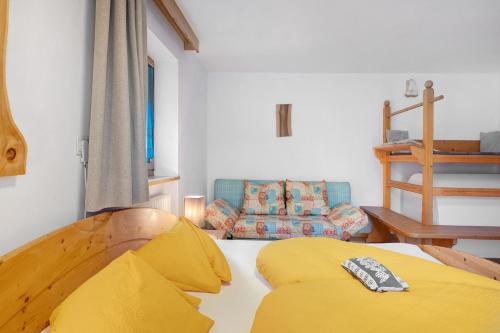 a bedroom with a yellow bed and a couch at Wohnung Rosengarten Heigler Hof in Collepietra