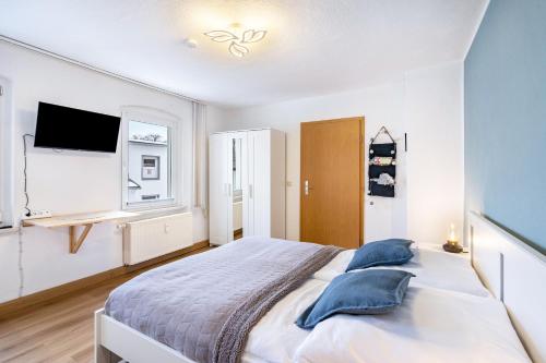 a white bedroom with a large bed and a tv at Ferienwohnung Steinstübchen in Bautzen