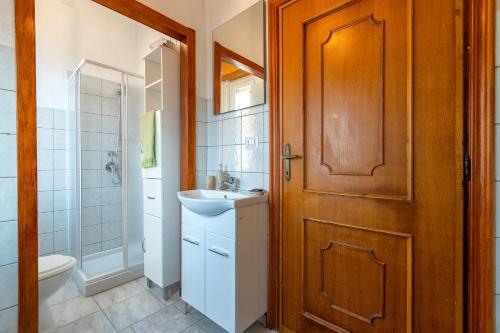 a bathroom with a toilet sink and a wooden door at The Domus vicino ad Alghero in Olmedo