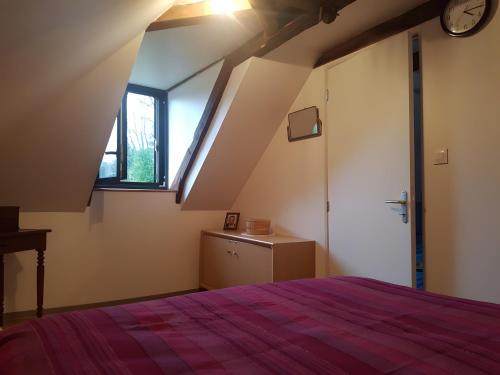 a attic bedroom with a bed and a window at Location Fermette in Goulles