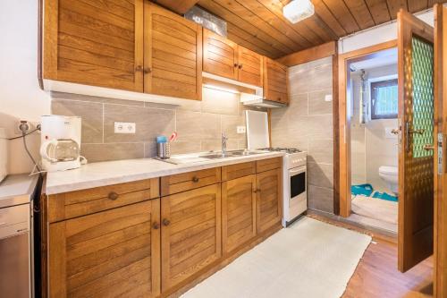a kitchen with wooden cabinets and a sink and a shower at Hochfügenblick-ski- und Wanderhütte in Hochfugen