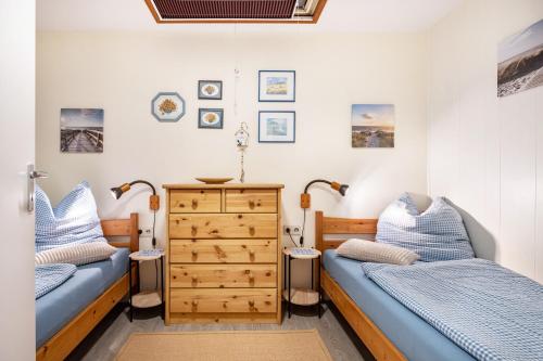 a bedroom with two beds and a dresser at Ferienwohnung Schmolei in Kronprinzenkoog