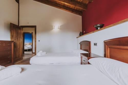 a bedroom with three white beds and a red wall at Fidalsa Rest Station in Burgos