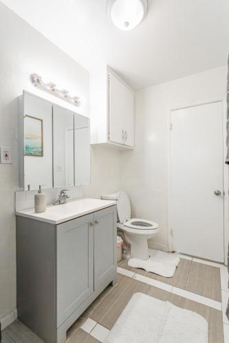 a white bathroom with a toilet and a sink at 2bd Suite Steps To Beach! - Private Patio & Grill! in Oceanside