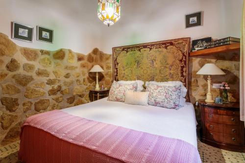 a bedroom with a bed and a stone wall at La Cuina De Paqui in Caserío Calandari
